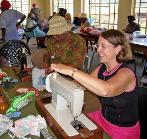 sewingmachingskills Ubuntu Centre is a hive of activity as African grandmothers busy themselves with hand sewn projects, while Beverley Barling teaches machine skills to Marjani Theledi