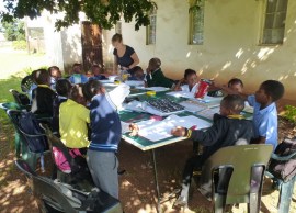 With no room indoors, Benedicte oversees 15 little ones with their homework and supplementary exercises, on a ping-pong table under a tree. 