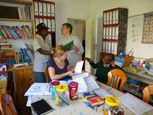 Samuel Fenyane (from the Teachers Union) and Vicky Bryant look at materials. Benedicte assists a young learner.